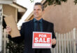 A "For Sale By Owner" sign posted in front of a residential house