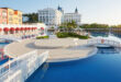 Aerial view of a luxurious coastal waterfront estate with large mansion and infinity pool