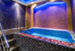 A split image showing various in-room hot tub setups, from a jetted bathroom tub to an open-concept bedroom hot tub, and a private balcony hot tub, illustrating the diverse options in room hot tub hotels.