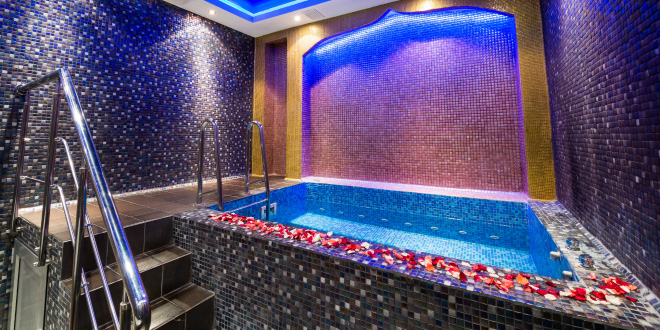 A split image showing various in-room hot tub setups, from a jetted bathroom tub to an open-concept bedroom hot tub, and a private balcony hot tub, illustrating the diverse options in room hot tub hotels.