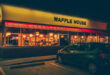 The iconic yellow sign of a Waffle House near me, glowing at dusk, inviting customers in.