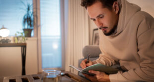 A focused person planning their financial habits to buy a dream home in 2026 using a budget planner.