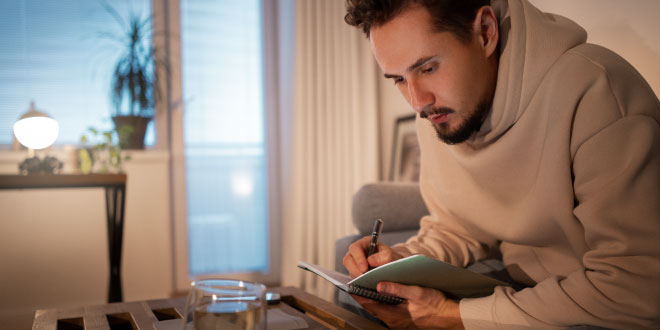 A focused person planning their financial habits to buy a dream home in 2026 using a budget planner.