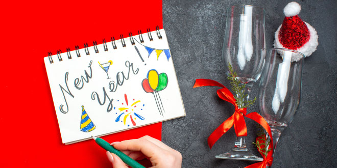 A business professional handwriting Professional New Year Wishes for Business Clients 2026 on a note card.